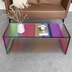 a colorful coffee table with a vase and flowers on it in front of a couch