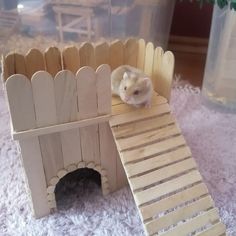 a toy hamster sitting on top of a wooden structure with a ramp in front of it