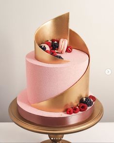 a pink and gold cake with berries, raspberries, and other toppings