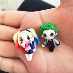 two small figurines are sitting on someone's hand, one is green and the other is white