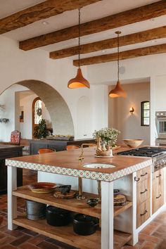 a kitchen with an island in the middle of it and lights hanging from the ceiling