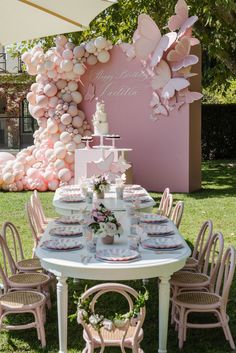 a table set up with pink and white balloons