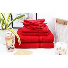 a stack of red towels sitting on top of a table next to a potted plant