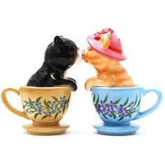 two ceramic cups with cats in them are kissing each other's noses on white background