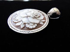 "This is an amazing cameo bezel set in Italian silver with a permanent bail (8mm). The bezel setting and bail have cz's encrusted around the entire rose cameo. It is carved in sardonyx shell and measures 35 mm (1.37\") round. This a beautiful piece to give as a gift or for yourself. It is carved by our carver, Romano. This pendant comes with a 18\" stainless steel chain. This is a rose that will live forever! This pendant comes with a black velvet box and certificate of authenticity. Item Number Silver Cameo Round Pendant Jewelry, Silver Cameo Jewelry With Round Pendant, Luxury Cameo Jewelry, Luxury Silver Cameo Jewelry, Silver Cameo Round Jewelry, Elegant Silver Cameo Jewelry, Luxury White Gold Cameo Jewelry, Live Forever, A Rose