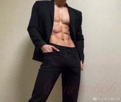 a shirtless man in a black suit posing for the camera with his hands on his hips