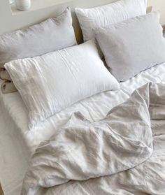 an unmade bed with white linens and pillows