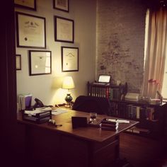 a desk with a lamp, books and pictures on the wall