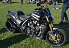 a motorcycle parked on top of a lush green field next to other motorcycles in the background