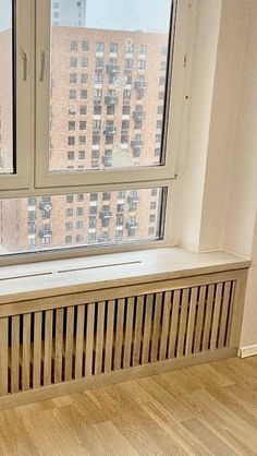 an empty room with a window, radiator and wood flooring in it