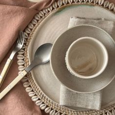 an empty cup and saucer on top of a white plate with pink napkins