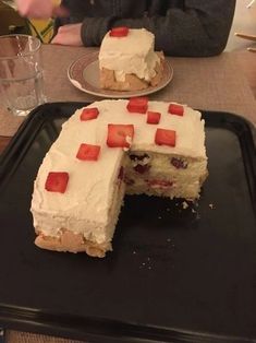 a piece of cake with white frosting and strawberries on it is cut into pieces