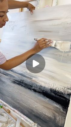 a woman is painting on an easel with white paint