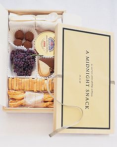 an open box filled with different types of cheese and crackers next to a card