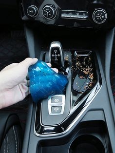 a hand is holding a blue object in the center console of a car, while it's being cleaned