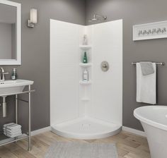 a white bath tub sitting next to a sink in a bathroom with gray walls and wooden floors