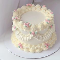 a three layer white cake with pink and green flowers on the top is sitting on a plate