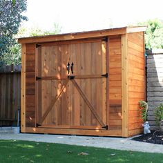 a large wooden shed with a sliding door on the side and green grass in front