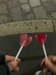 two candy lollipops being held by someone's hand on the street