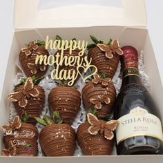 a box filled with chocolate covered strawberries next to a bottle of wine