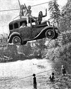 an old black and white photo of people riding on the back of a car over a river