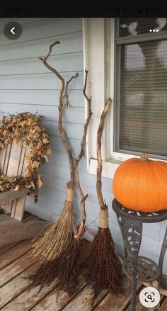 some pumpkins and brooms are sitting on the porch