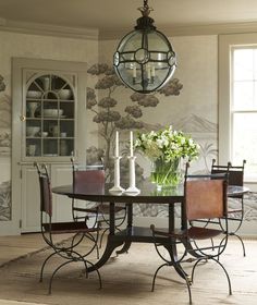 a dining room table with chairs and a vase filled with flowers on top of it