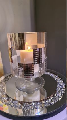 a candle that is sitting on top of a glass plate with some diamonds around it