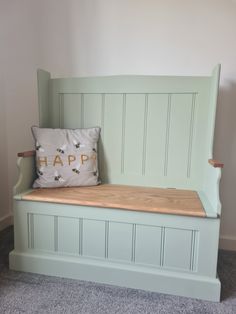 a wooden bench with a happy pillow on it's seat in front of a wall