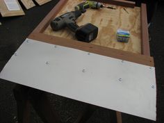 a table with some tools on it and plywood boards in the back ground next to it