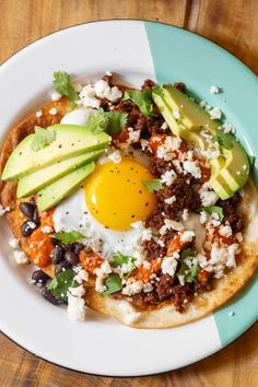 an egg is sitting on top of a tortilla with black beans and avocado