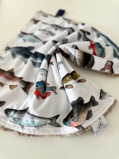 two pieces of cloth with fish on them sitting on top of a white countertop