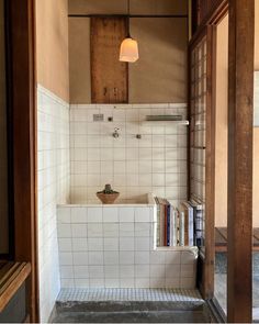 an open door leading to a bathroom with books on the counter and shelves in it