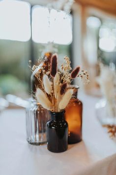 two vases filled with dried flowers on top of a table