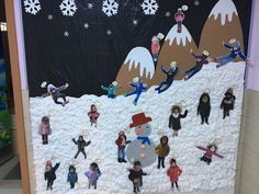 a group of people standing in front of a bulletin board with snowmen on it