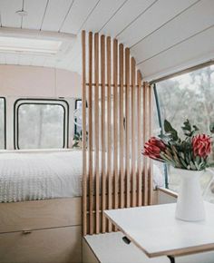 the interior of a camper with a bed, desk and flowers in vases