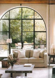 a living room filled with furniture and lots of windows overlooking the trees outside in front of it