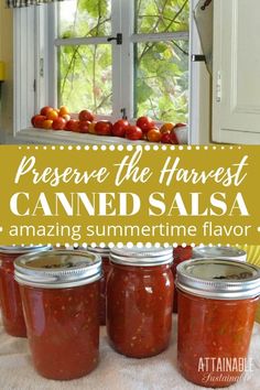 four jars filled with canned salsa sitting on top of a table next to an open window