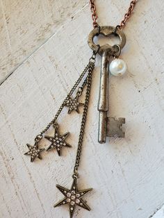 This vintage repurposed skeleton key necklace is really gorgeous!  The chain is copper tone metal link chain, about 32 inches long.  The key is 3 inches long, and the chain with rhinestone brass star charms is about 4 inches long.  There is a white glass pearl charm on the key.  The skeleton key is in perfect condition!  This is a really unique necklace, and you will love it! Skeleton Key Necklace Diy, Crafts Using Keys, Key Necklace Aesthetic, Skeleton Key Crafts, Old Key Crafts, Antique Key Necklace, Skeleton Key Jewelry, Key Necklaces, Charm Necklace Diy