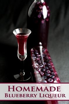 blueberry liqueur in a wine glass next to a bottle with the words homemade blueberry liqueur on it