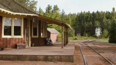 a small train station with a bench on the platform and trees in the back ground