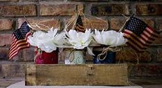 some white flowers are in a red, white and blue mason jar with an american flag