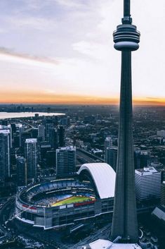 an aerial view of a city with tall buildings and a tower in the background at sunset