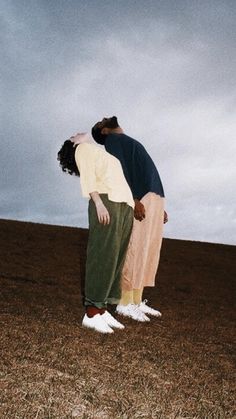 two people standing in the middle of a field with their heads touching each other's foreheads