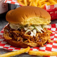 a pulled pork sandwich with coleslaw and french fries