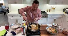 a man is cooking some food in a pan on the kitchen counter with other dishes and utensils