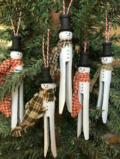 three snowman ornaments hanging from a christmas tree