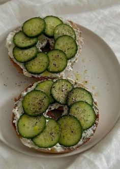 two pieces of bread with cucumbers on them sitting on a plate next to each other