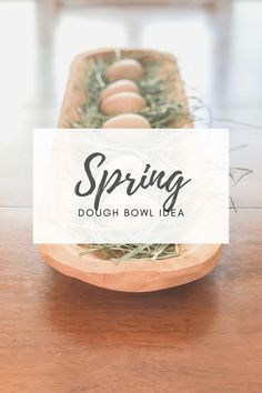 a bowl filled with eggs sitting on top of a wooden table next to a white sign that says spring dough bowl idea