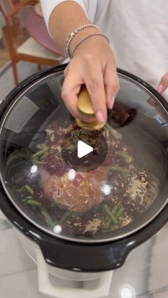 a woman is cooking food in a large pot on the stove with a video screen